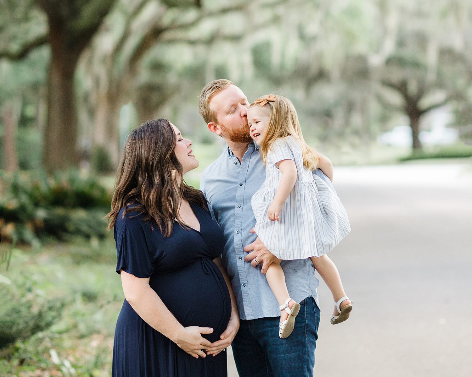 dad kissing two year old with pregnant mom next to dad in savannah family maternity photograph